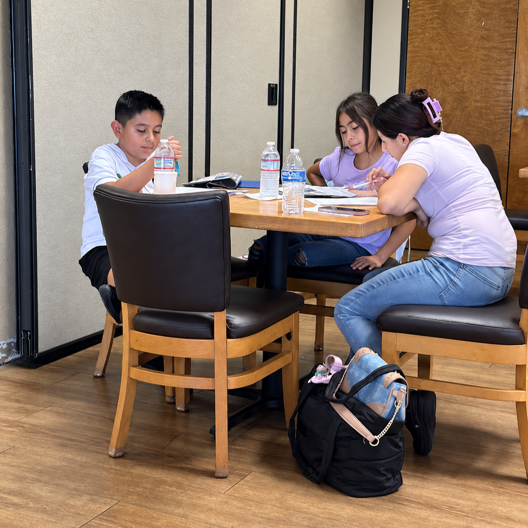 Students working together at a table with a tutor during Homework Help