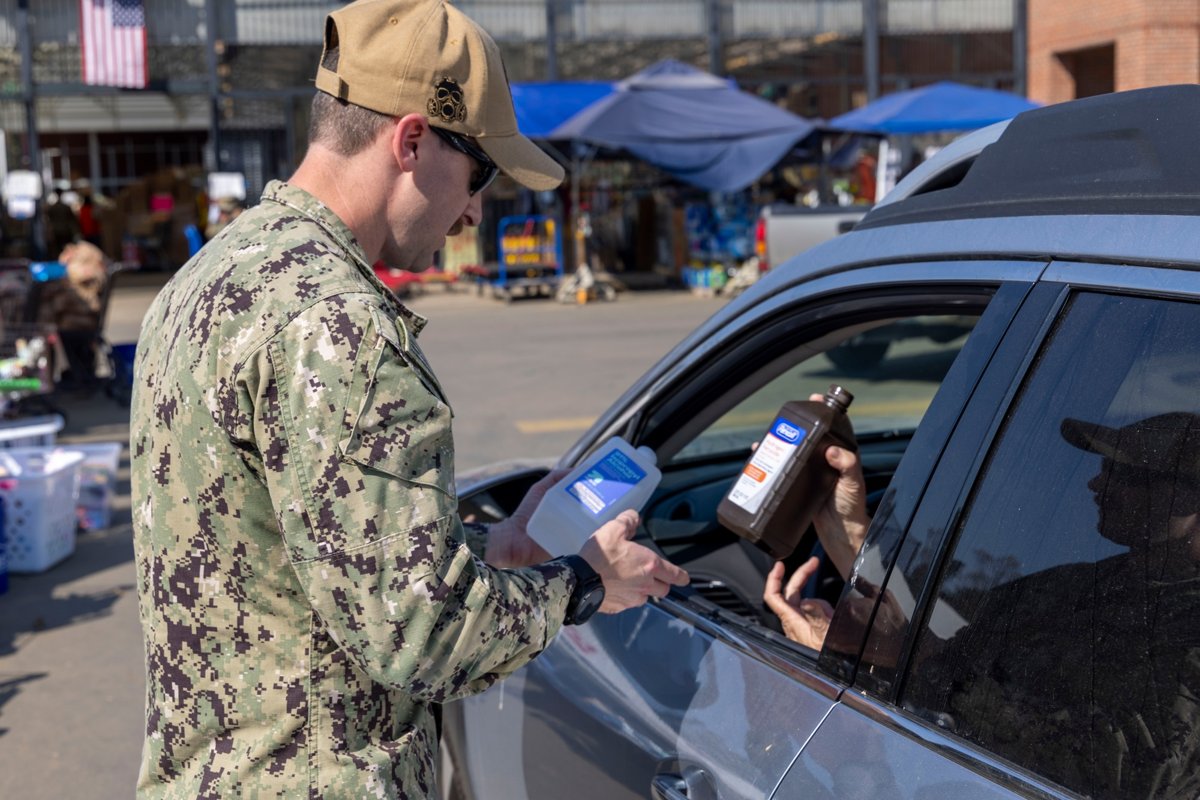 A U.S. Navy service member handing supplies to a resident in a vehicle at a community assistance event in Black Mountain, North Carolina